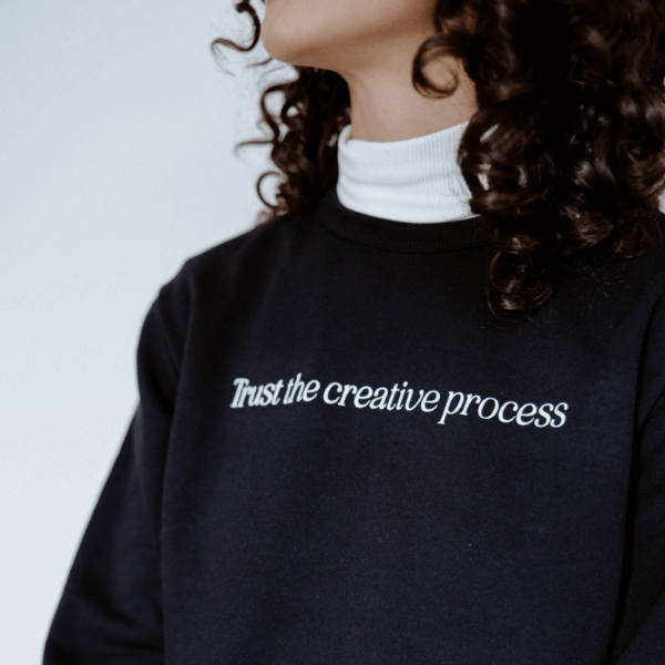 Girl wearing a sweatshirt with "Trust the creative process" written on the chest