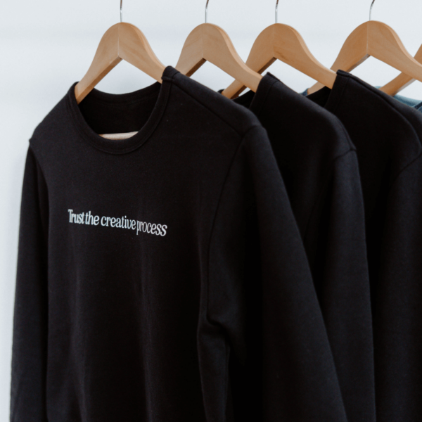 black sweatshirt with the words "Trust the creative process" on the chest area