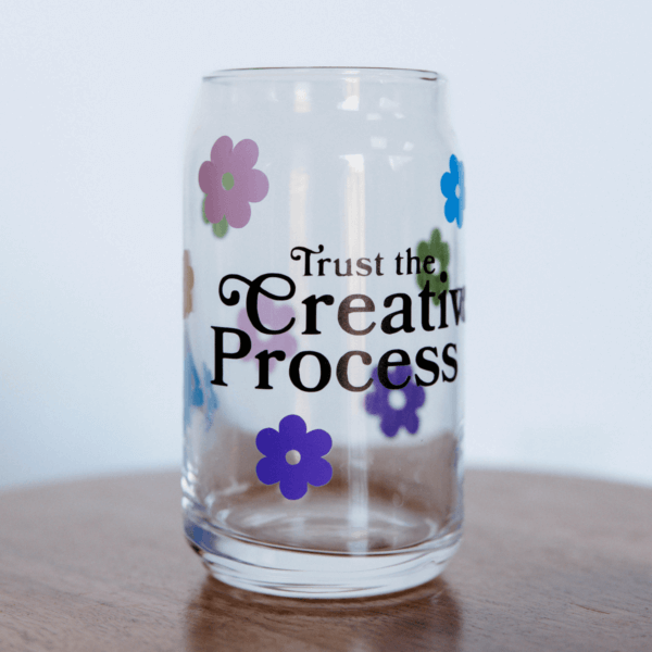 Drinking glass with colorful flowers and the words "Trust the Creative Process".