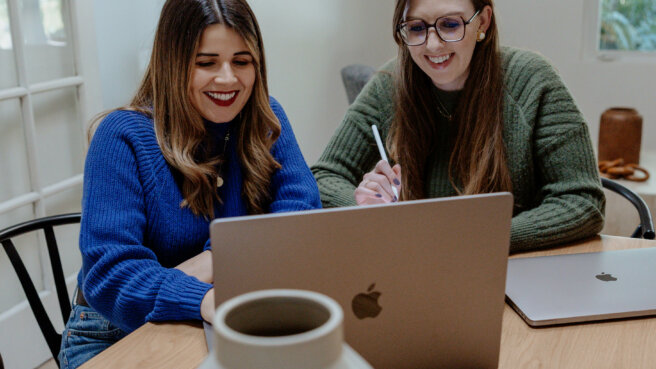 Two women on a marketing team using AI tools on a laptop